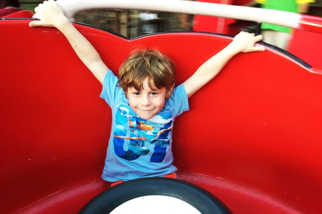 Disneyland is the perfect day trip from Los Angeles with kids. Little boy in a blue shirt on a red tea cup ride.